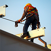 A worker straddling a steel beam while doing construction.