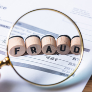 Magnifying glass hovering over blocks that spell “Fraud”