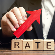 A man holds a red arrow up above the word Rate and a wooden house.