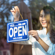 Woman hanging open sign in business window