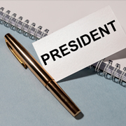 President name tag next to a pen and on top of a blank notebook