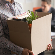 An employee carries a box of personal items out of an office.