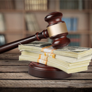 Wood gavel resting on large stack of money.