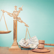 Scale of Justice weighed down on one side with money. Gavel and clapperboard also pictured.