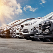 Row of cars parked under a sunny sky.
