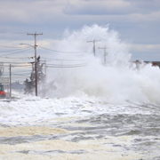 Flood waters crash against utility poles.