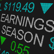 A stock market ticker with the words “Earnings Season” in white on a black board in the middle with other stock ticker symbols and prices surrounding it