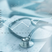 Stethoscope on top of medical charts overlaid with financial chart graphics.