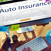 Auto insurance website or form displayed on a computer screen with keyboard and desk items visible.