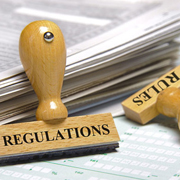 Two rubber stamps with the words imprinted with the words rules and regulations next to a stack of papers.