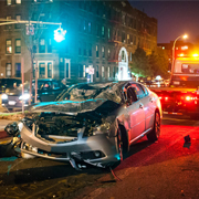 Damaged car at night, tow truck nearby.