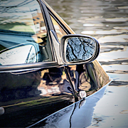 Flood waters nearly reach the side view mirror on a trapped car