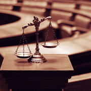 Bronze scales of justice on a courtroom pedestal.