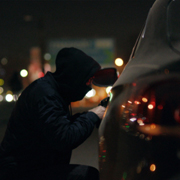 Thief breaking into a car at night